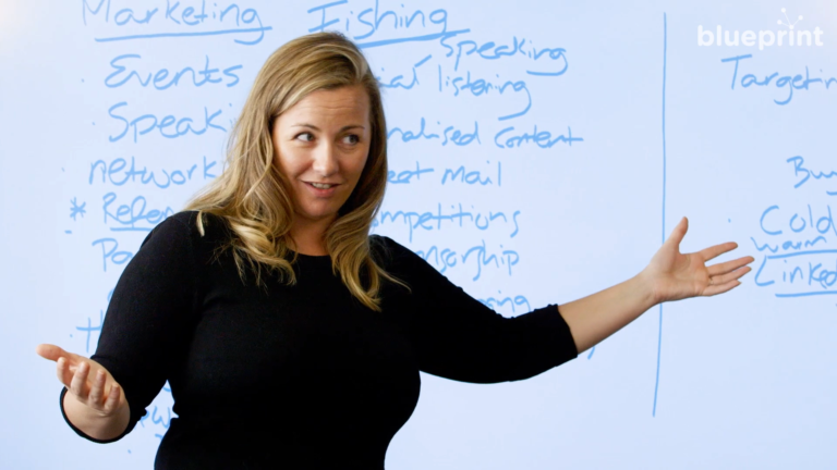 Woman gestures in front of whiteboard